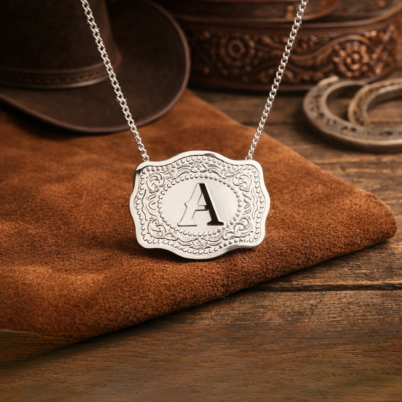 Silver necklace with an engraved pendant featuring the letter 'A' on a wooden surface.