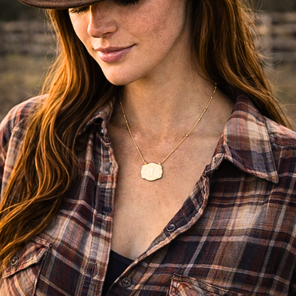 Woman wearing a plaid shirt and gold necklace with a blurred background